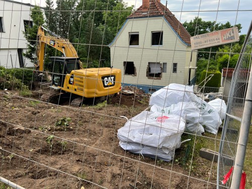 Bagger bei Sanierungsarbeiten mit Asbest-Entsorgungssäcken auf abgesicherter Baustelle