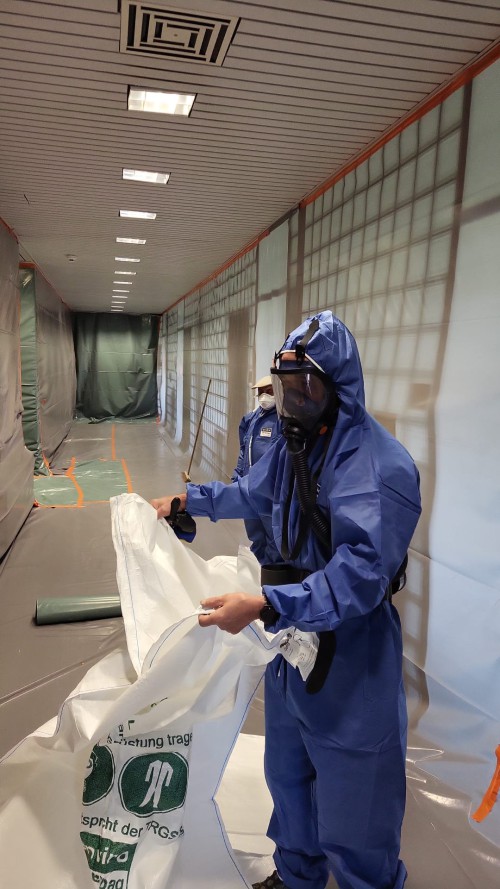 Arbeiter in Schutzanzug bei der professionellen Schadstoffsanierung in abgesichertem Bereich