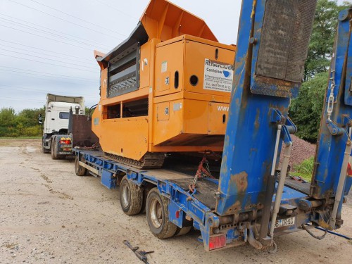 Orange Siebanlage auf blauem Tieflader für Spezialtransport von Recycling-Equipment
