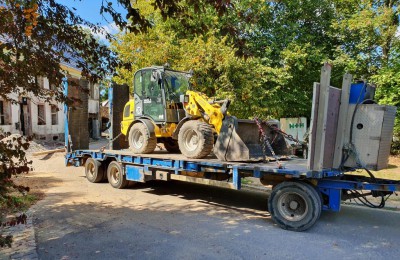 Gelber Radlader auf blauem Tieflader-Anhänger für professionelle Maschinentransporte