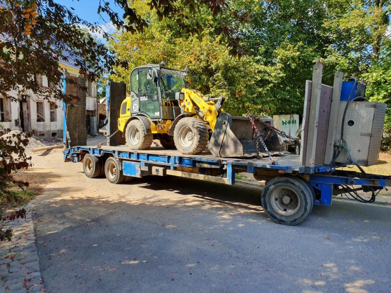 Gelber Radlader auf blauem Tieflader-Anhänger für professionelle Maschinentransporte