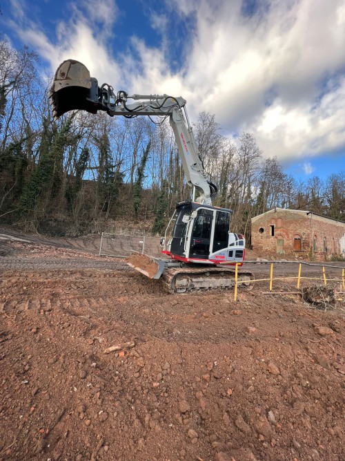 Weißer Minibagger bei Erdarbeiten - kompakte Baumaschine zur flexiblen Miete